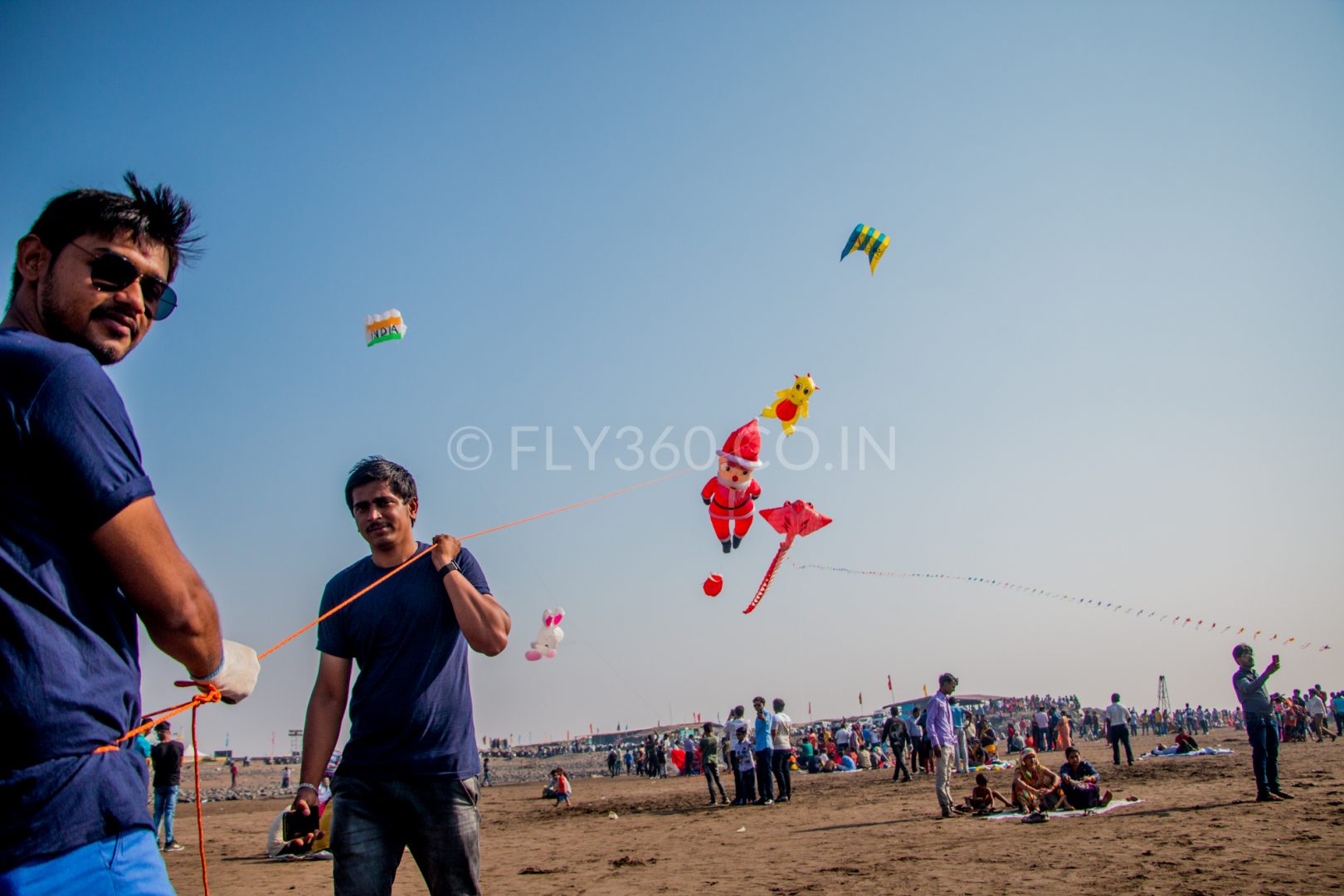 Two men flying kites on Suvali beach in Gujarat during a tourism kite festival