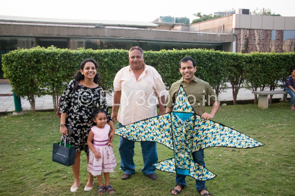 A family holding a bird-shaped kite on a lawn after a Fly360 birthday kite making workshop