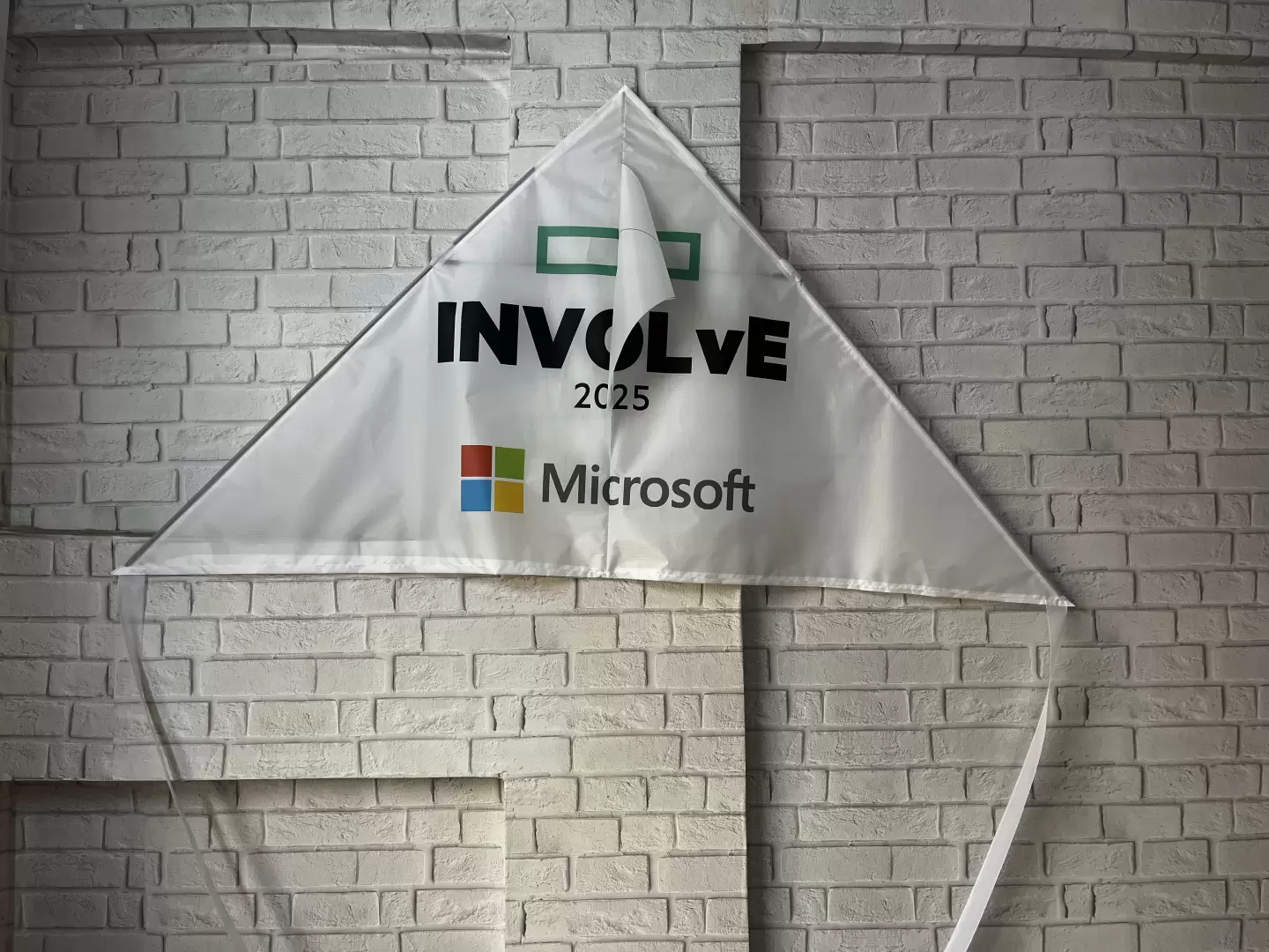 White delta kite printed with INVOLvE 2025 and the Microsoft logo, made by Fly360