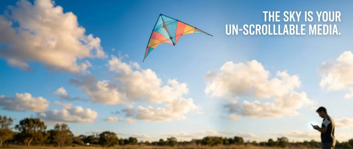 imagedesktop An outdoor photograph capturing a massive, custom-engineered FLY360 delta kite with "MADE IN INDIA" written on it, flying high over a large crowd at an outdoor festival in Vapi, Gujarat, India. The kite is patterned with the Indian flag and features prominent blue "FLY360" text above green and orange "MADE IN INDIA" text. A text overlay in the sky reads: "THE SKY IS YOUR UN-SCROLLABLE MEDIA." Smaller inset images on the left and right show men engineering the kite on computers using 3D design software, and a ground-level banner reads "FLY360 - KITE ENGINEERING & MANUFACTURING SINCE 1996